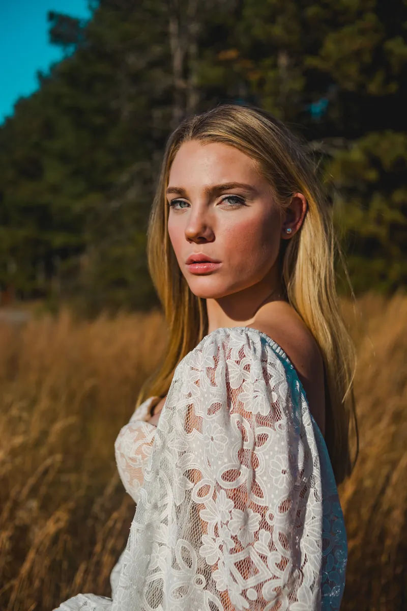 A woman in a white dress in a field on a plain day